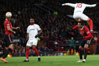 Sevilla's Moroccan forward Youssef En-Nesyri headers ball to score a second goal, deflected in for an own goal off Manchester United's English defender Harry Maguire (L) during their UEFA Europa league quarterfinal first leg at Old Trafford stadium on Thursday. (AFP)