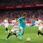 Luka Modric of Real Madrid passes the ball under pressure from Marcos Acuna of Sevilla FC during the LaLiga Santander match between Sevilla FC and Real Madrid CF at Estadio Ramon Sanchez Pizjuan on April 17, 2022 in Seville, Spain. (Photo by Fran Santiago/Getty Images)