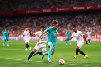 Luka Modric of Real Madrid passes the ball under pressure from Marcos Acuna of Sevilla FC during the LaLiga Santander match between Sevilla FC and Real Madrid CF at Estadio Ramon Sanchez Pizjuan on April 17, 2022 in Seville, Spain. (Photo by Fran Santiago/Getty Images)