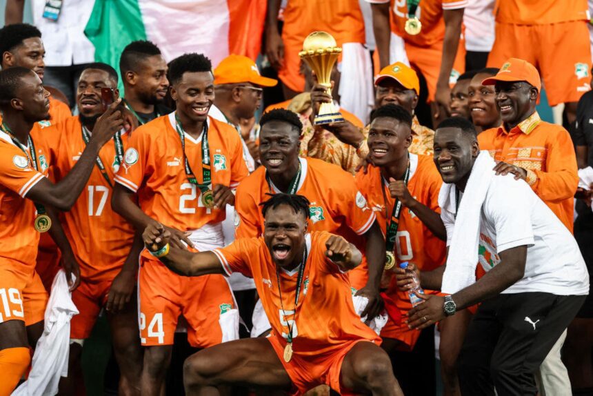 President of Ivory Coast Alassane Ouattara (C) lifts the Africa Cup of Nations trophy on the podium after Ivory Coast won the Africa Cup of Nations (CAN) 2024 final football match between Ivory Coast and Nigeria at Alassane Ouattara Olympic Stadium in Ebimpe, Abidjan on February 11, 2024. (Photo by FRANCK FIFE/AFP via Getty Images)